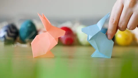 Two adorable paper Easter bunnies meet infront of colorful Easter eggs. Stock Footage 149062010