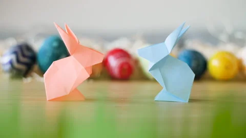 Two adorable paper Easter bunnies meet infront of colorful Easter eggs. Stock Footage 149062710