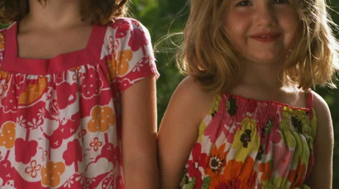 Two adorable sisters wave to the camera at the park 스톡 동영상 33834745