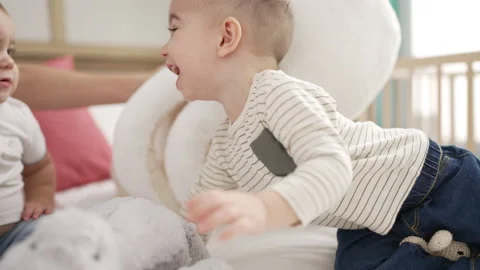 Two adorable toddlers sitting on bed playing at bedroom Video stock 225068142