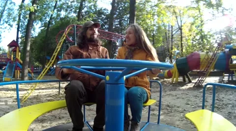 Two adults have fun on the carousel in a park close view Stock Footage 68674060