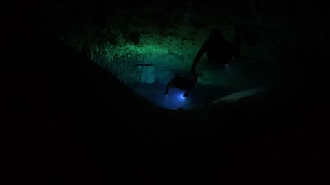 Two adventurous divers swimming and exploring a dark, submerged cave with 스톡 동영상 332002729