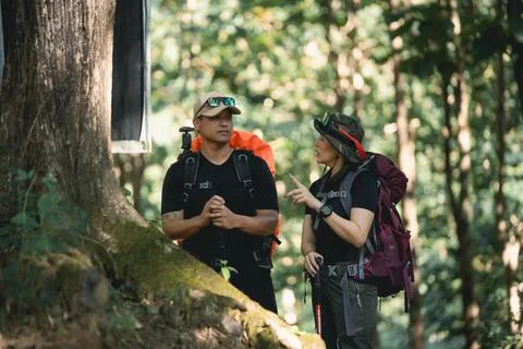 Two Adventurous Hikers Engaged in a Conversation in Lush Green Forest Surro.. Foto stock