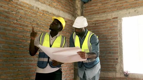 Two African construction workers in safety gear use a spirit level on a brick Stock Footage 321448813