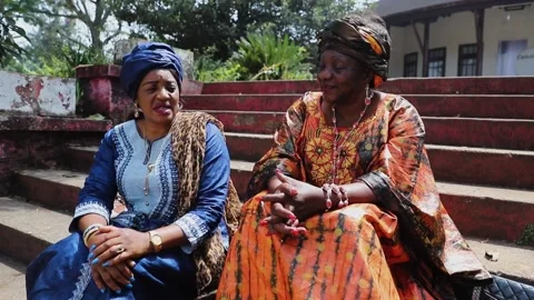 Two African ladies are conversing sitting on the stairs, African life Stock Footage 202605006