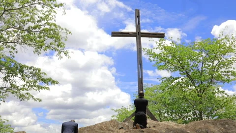Two African men praying in front of a cross on top of big rocks Stock Footage 265711912
