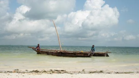 Two African men setting off to the open sea on a traditional sailing boat (Dhow) Stock Photos