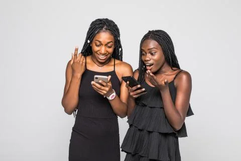 Two african young girls check out amazing article on web page via cellular, h Stock Photos