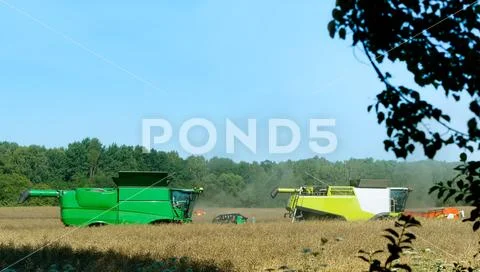 Two agricultural machines operate in the field, grain harvesting machines ope Stock Photos