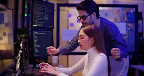 Two AI developers working late night on machine learning code in tech office Video stock 310483649