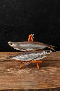 Two air-dried sabrefish on serving stand on black background Stock Photos
