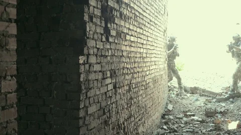 Two air soft men go through door hole training fight in urban territory Stock Footage 127884122