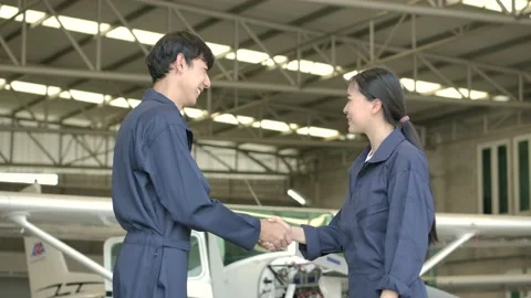 Two aircraft engineer shaking hands in airport hangar. Video stock 141985978