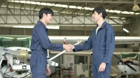 Two aircraft engineer shaking hands in airport hangar. Video stock 141987135