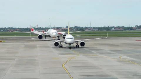 Two airliners in queue to terminal, Lion Air airplane taxiing on background Stock Footage 309358976