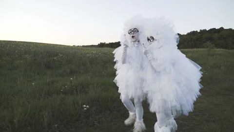 Two amusing clowns mime in white air suits are having fun on a country road in Video stock 92181822