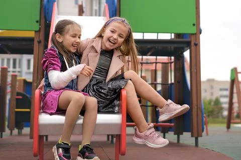Two amusing cool sisters laugh sincerely and have fun on playground. Stock Photos