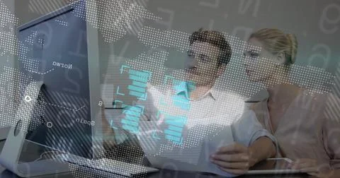 Two analysts reviewing data at desk, man pointing at monitor starting overlay Stock-Fotos