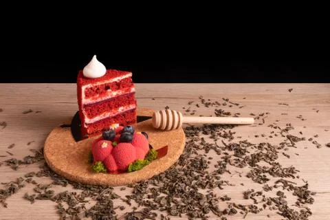 Two appetizing delicious red cakes and honey dipper on a cork stand Stock Photos
