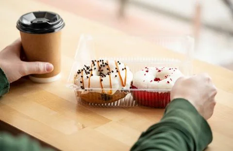 Two appetizing donuts and coffee in male hands, close-up. Stock Photos