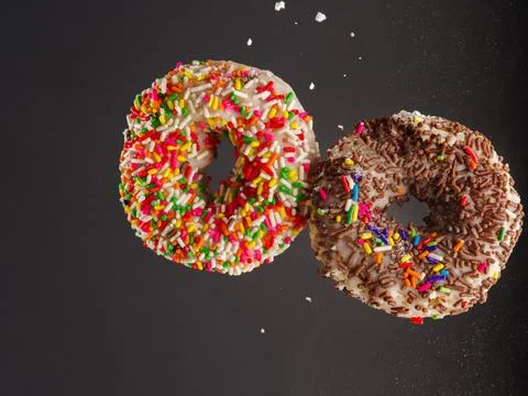 Two appetizing donuts on a gray background in a frozen flight. Sweet food, ca Stock Photos