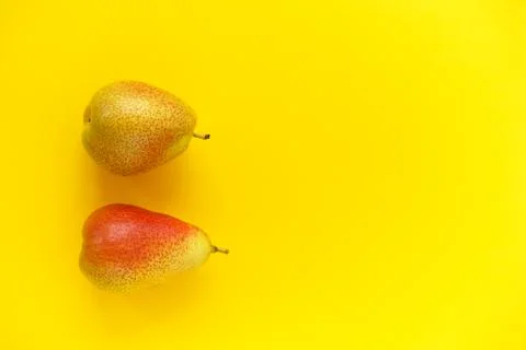 Two appetizing ripe pears with red side on a yellow background. Stock Photos