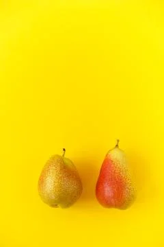 Two appetizing ripe pears with red side on a yellow background. Stock Photos