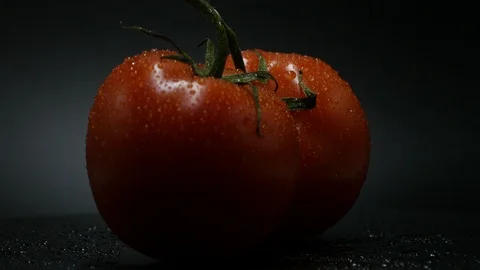 Two appetizing ripe tomatoes on a mirror black background. Rotating table Stock Footage 108909068