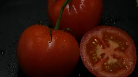 Two appetizing ripe tomatoes on a mirror black background. Rotating table 動画素材 108909292