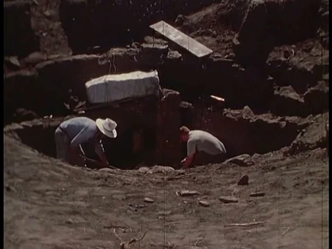 Two archaeologists, digging, attempt to isolate and shape a stratigraphicƒ Video stock 75769333