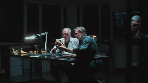 Two archaeologists take measurements of ancient human skull, use tablet computer Stock Footage 283484554