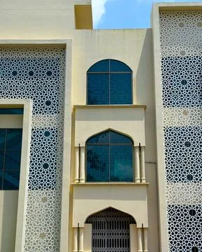 Two arched windows and decorative geometric patterns adorn the facade of a li Фото