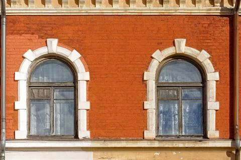 Two arched windows on a brick wall. Stock Photos
