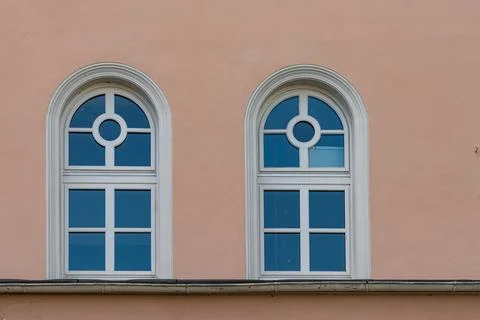 Two arched windows on a pastel colored wall in a city Stock Photos