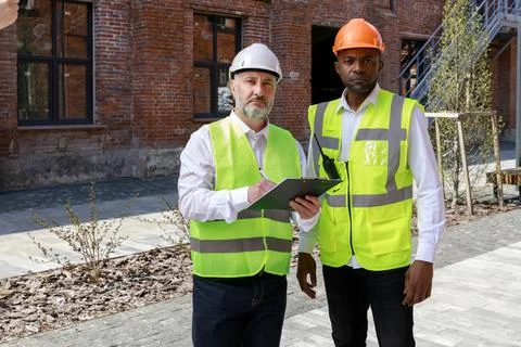 Two architect standing near construction builing. Coworkers sharing Stock Photos
