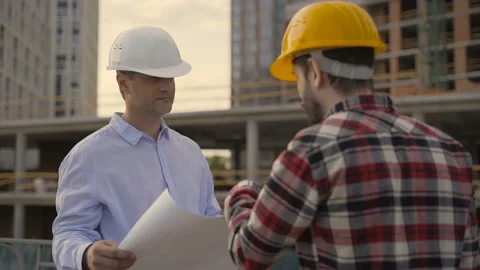 Two architects analyze blueprint of building standing indoors. They hold Stock Footage 112027862