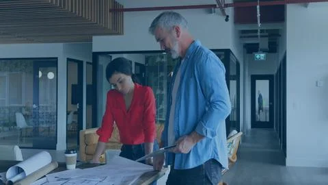 Two architects are collaborating over plans in flat architecture office, with Stock Photos