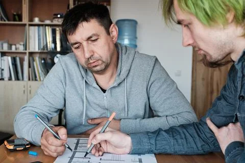 Two architects make marks on the plans of the building. Stock Photos