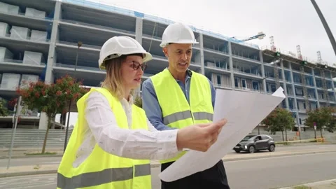 Two architects reviewing blueprints at construction site Stock Footage 317626477