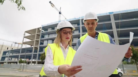 Two architects studying blueprints on a construction site Stock Footage 317626548