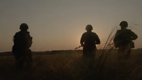 Two armed men with weapon walking across field after combat operation back view. Stock Footage 169923216