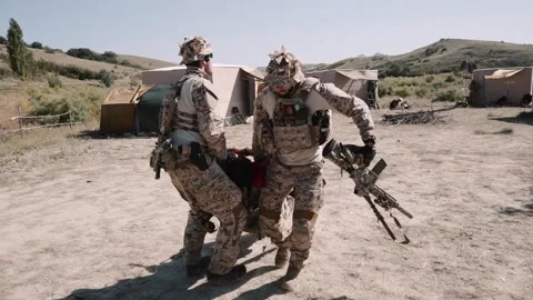 Two armed soldiers are dragging a wounded man. in a military camp Stock Footage 248233752