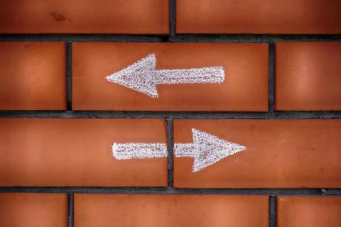 Two arrows pointing forward and backward drawn on bricks Stock Photos