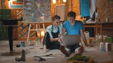 Two artists using laptop discussing art in workshop Stock Footage 129313142