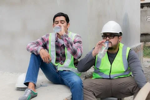 Two Asian builder workers wearing safety reflected vest and helmet tired th.. Stock Photos