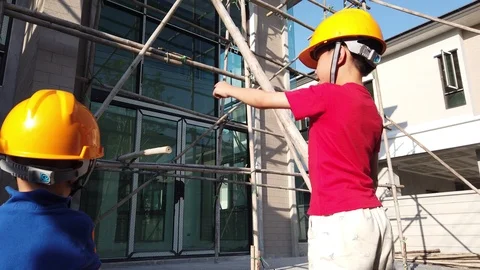 Two asian children boys wearing constructor helmet at construction site or build Stock Footage