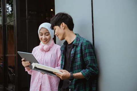 Two Asian college students using a pad and books Stock Photos