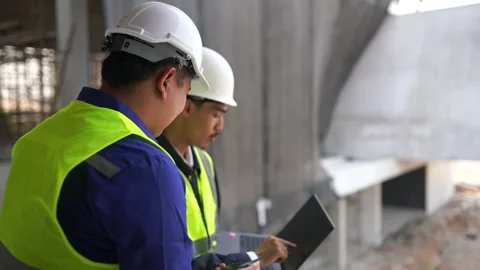 Two Asian construction engineers or site supervisors wearing hard hats and .. Stock Footage 333579695