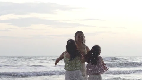 Two Asian daughters running to hug their smiling mother on beach Vídeos de archivo 340185431