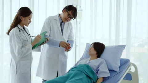 Two Asian doctors standing and talking to patients Stock Footage 120065908